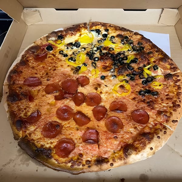 A Bruno's Pizzeria pizza in a box, half pepperoni and half black olives with banana peppers.
